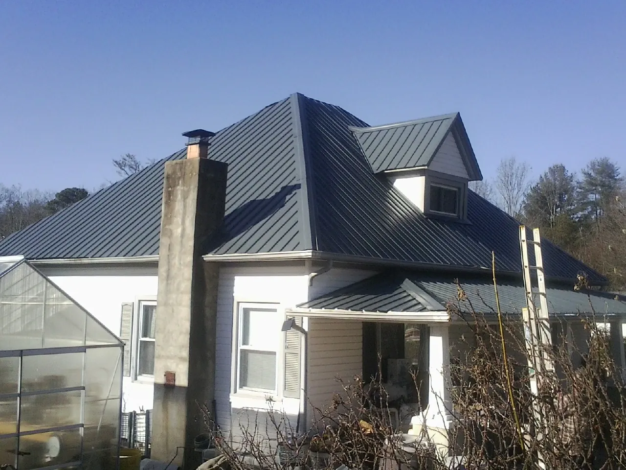Dark blue standing seam metal roof on a white farmhouse with dormer — Slate & Tile Roof Repair by Roofing Brothers in Bruceton Mills
