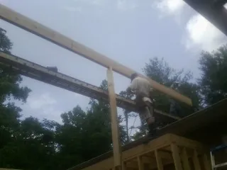 Carpenter setting a ridge beam over a new addition frame — Ice Dam Removal by Roofing Brothers in Bruceton Mills