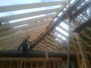 Rafters going up over a new addition with a worker on the wall in Bruceton Mills
