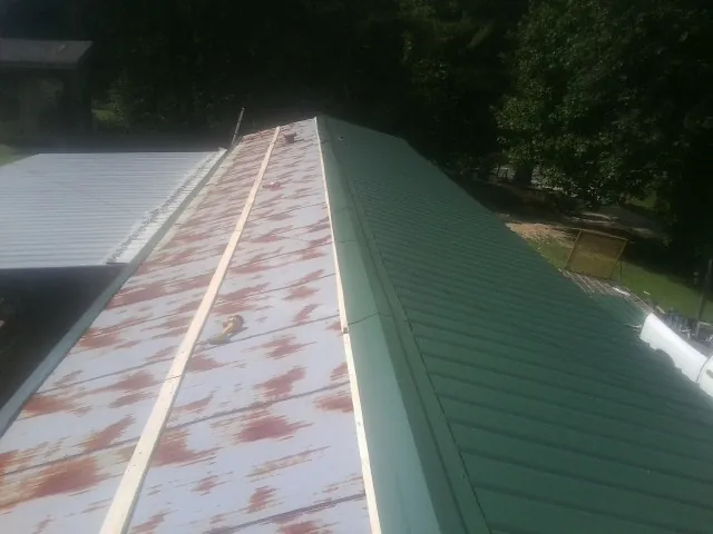 Old rusted panels beside newly installed green metal roofing — Wind Damage Roof Repair by Roofing Brothers in Bruceton Mills