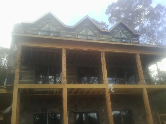 Dormers and porch framing on a large log home under construction — Roof Coating work by our crew in Bruceton Mills