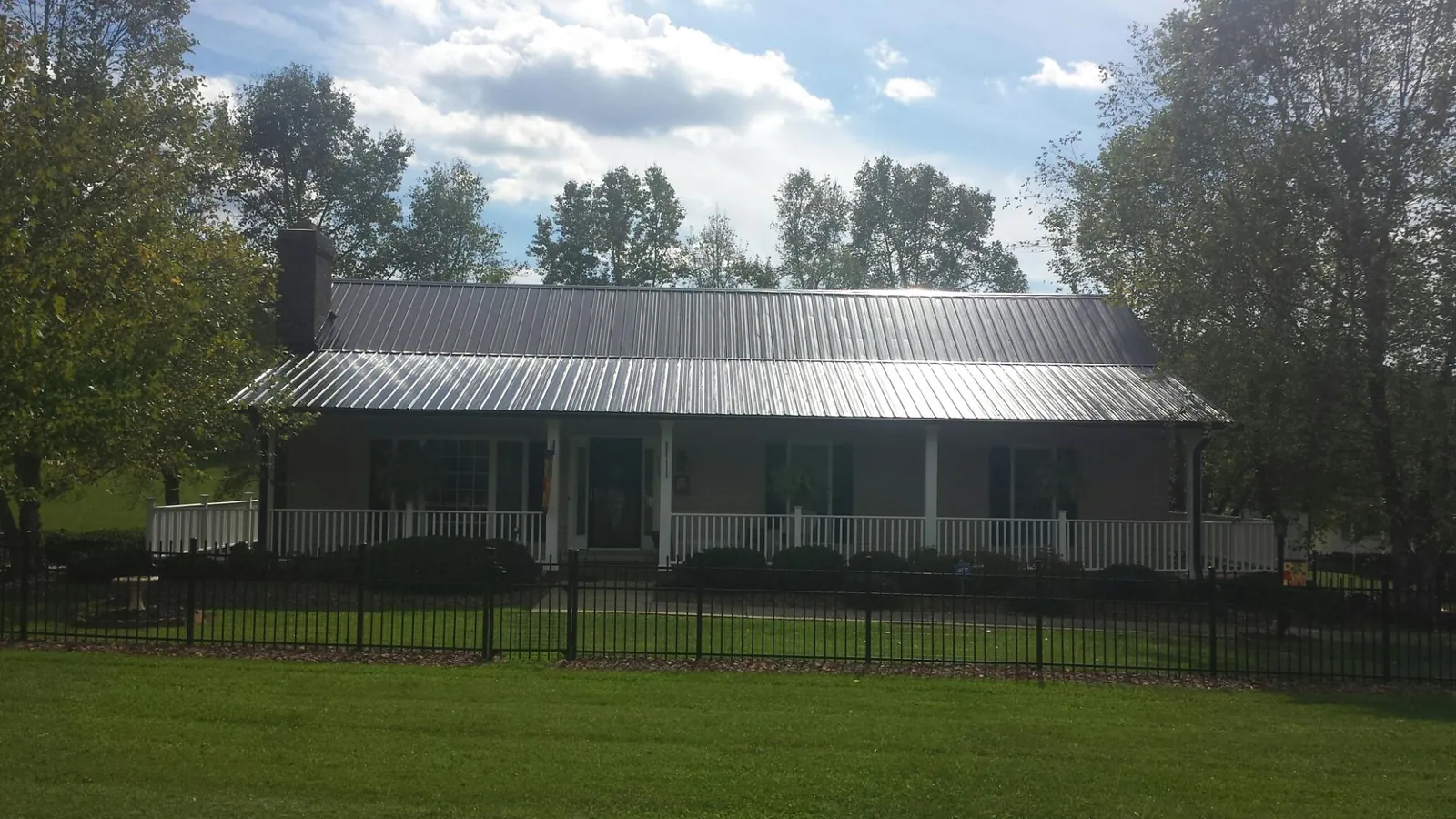 Gray metal roof on a brick ranch with a full width front porch — Gutter Guard Installation work by our crew in Bruceton Mills