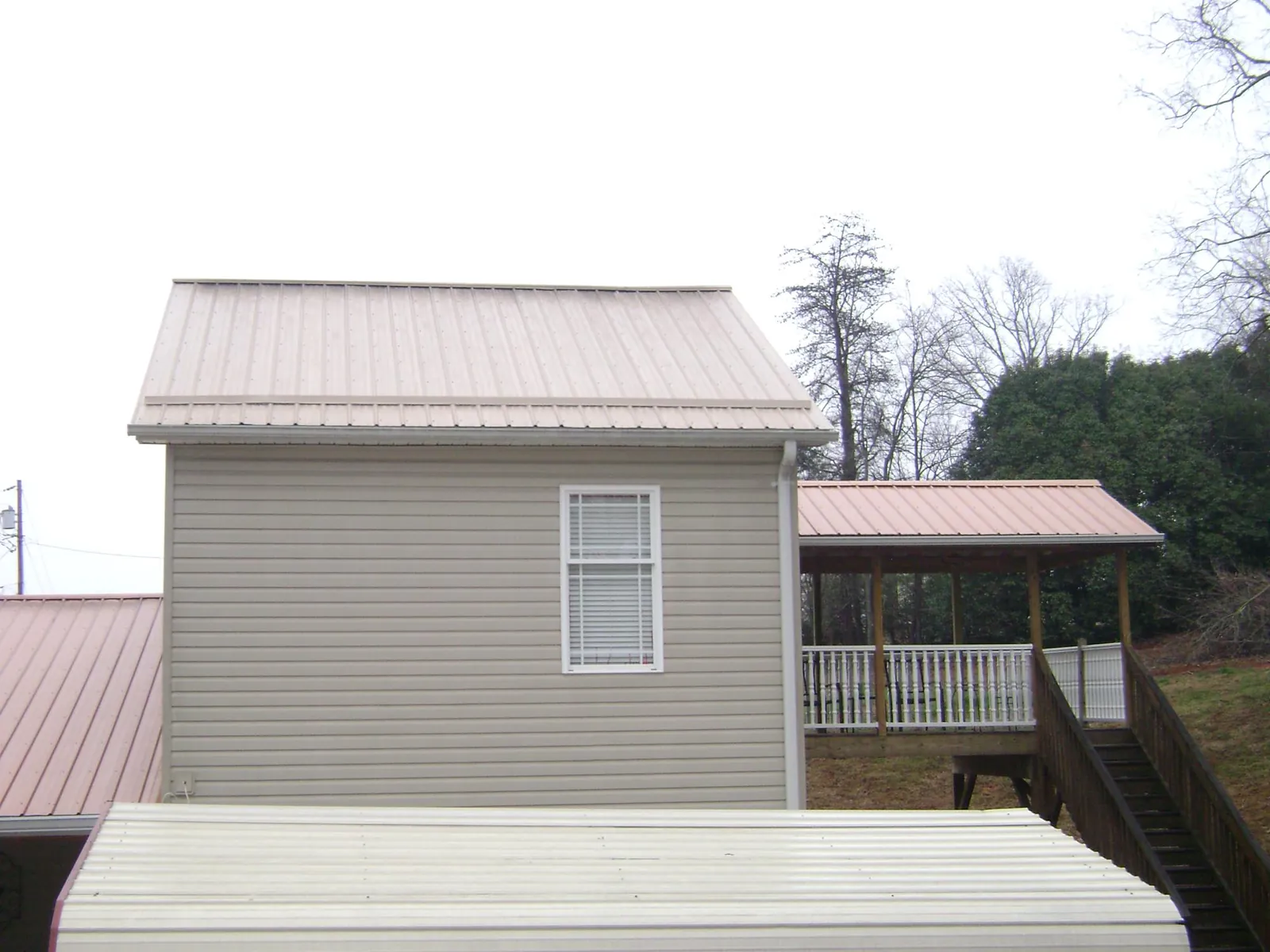 Tan metal roofs on a two story addition and attached porch, from a Roof Replacement job in Bruceton Mills