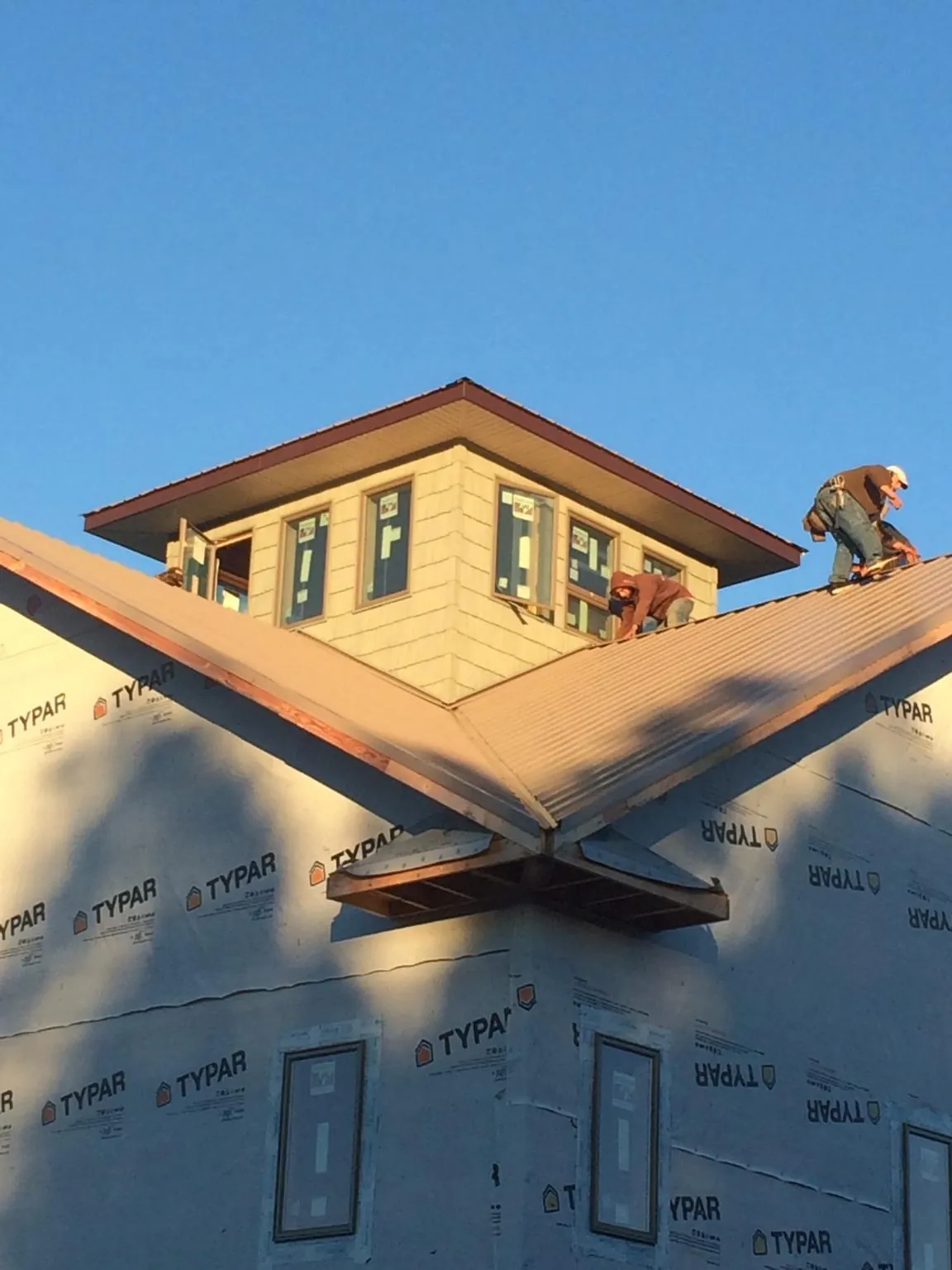 Roofers working around a rooftop cupola on a new metal roof at sunset — Roof Waterproofing in Bruceton Mills by Roofing Brothers